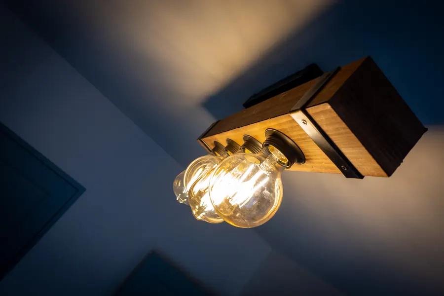 L'applique en bois et son ampoule à filament, allumée