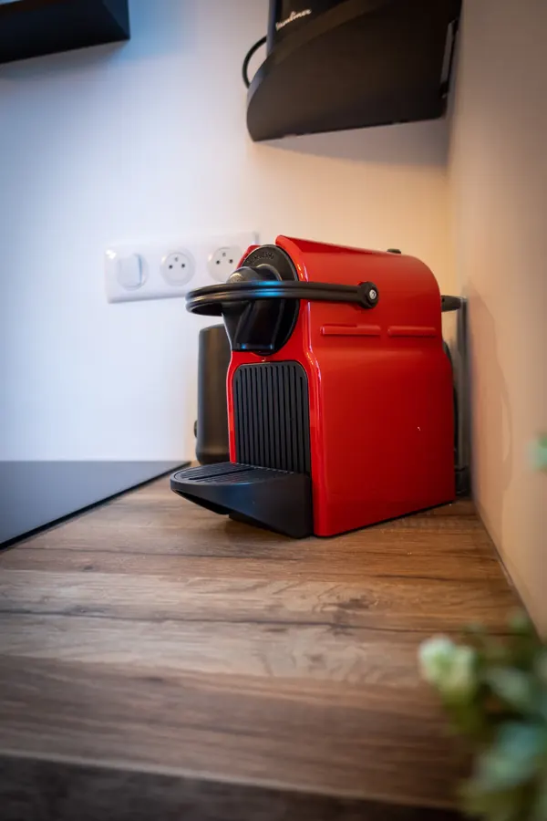 La machine à café rouge sur le plan de travail en bois